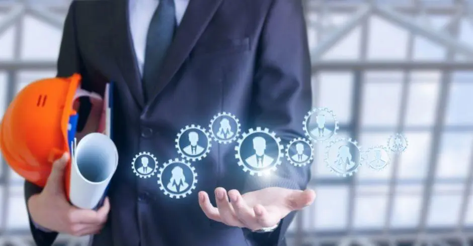 Person in a suit holding a construction hat and blueprints