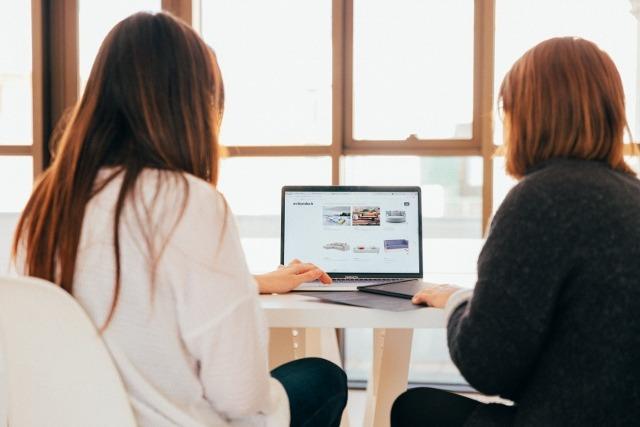 Two women looking at financial management software on a laptop togethe