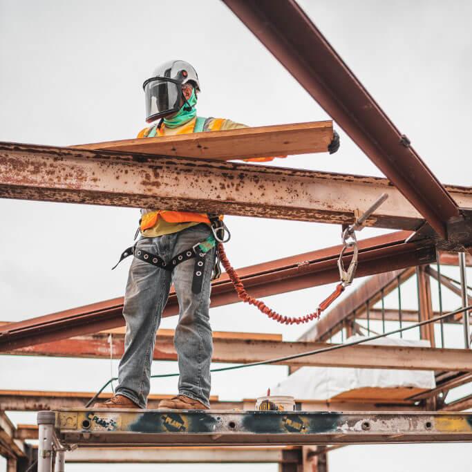 Job_-Management-2 Construction worker standing on scaffolding high up on a job site.